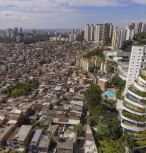 Vista aérea mostrando contraste entre favela densamente ocupada e edifícios de alto padrão em São Paulo.
