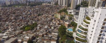 Vista aérea mostrando contraste entre favela densamente ocupada e edifícios de alto padrão em São Paulo.