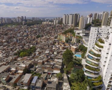 Vista aérea mostrando contraste entre favela densamente ocupada e edifícios de alto padrão em São Paulo.
