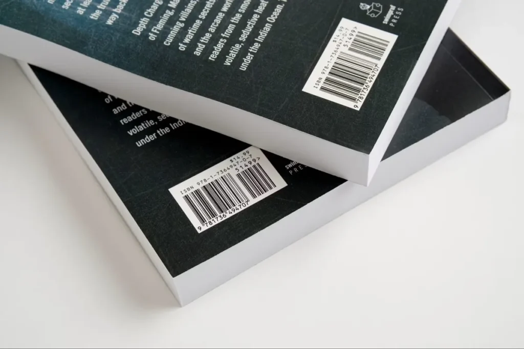 Dois livros empilhados mostrando a contracapa escura com códigos de barras ISBN impressos em etiquetas brancas.