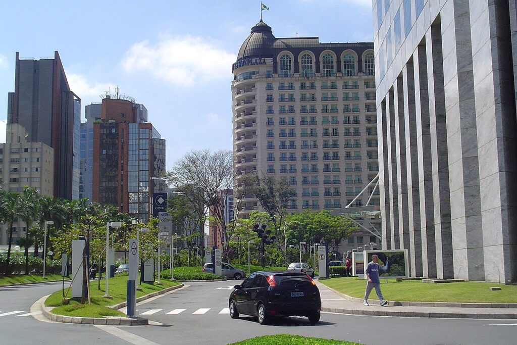 Prédios modernos na região da Avenida Nações Unidas, em São Paulo, com carros, pedestres e área verde ao redor.