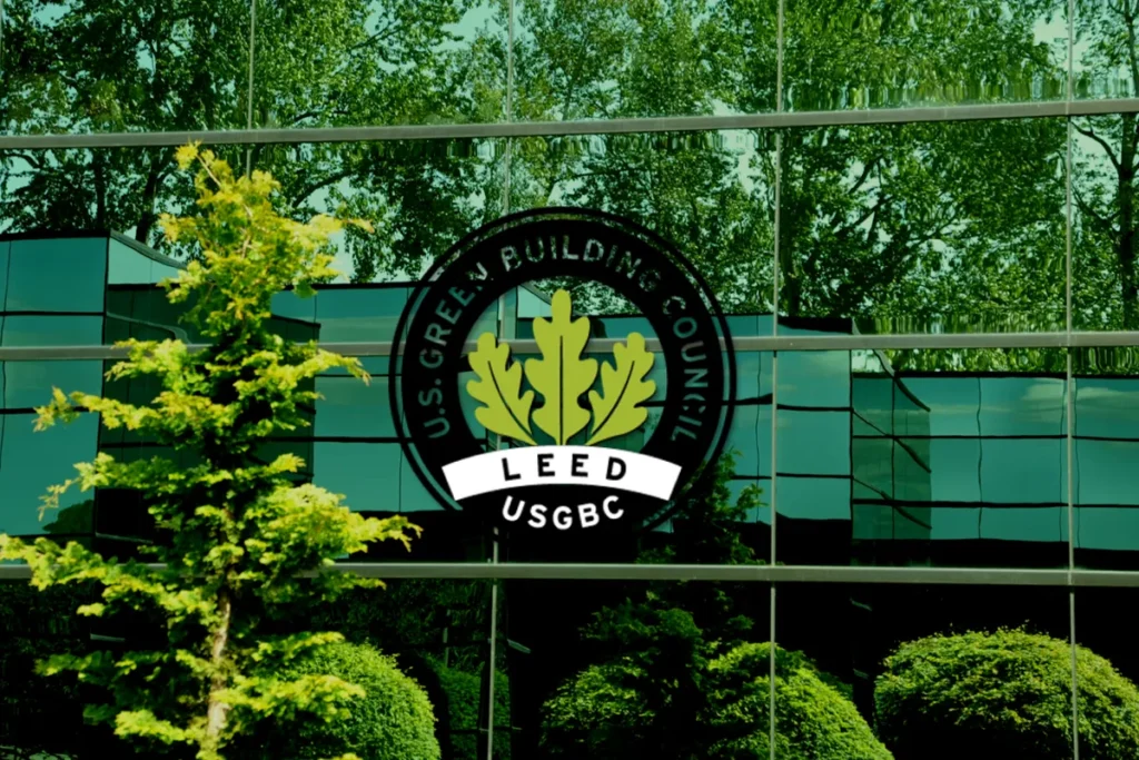 Logotipo da certificação LEED USGBC em fachada espelhada de edifício moderno com árvores refletidas no vidro