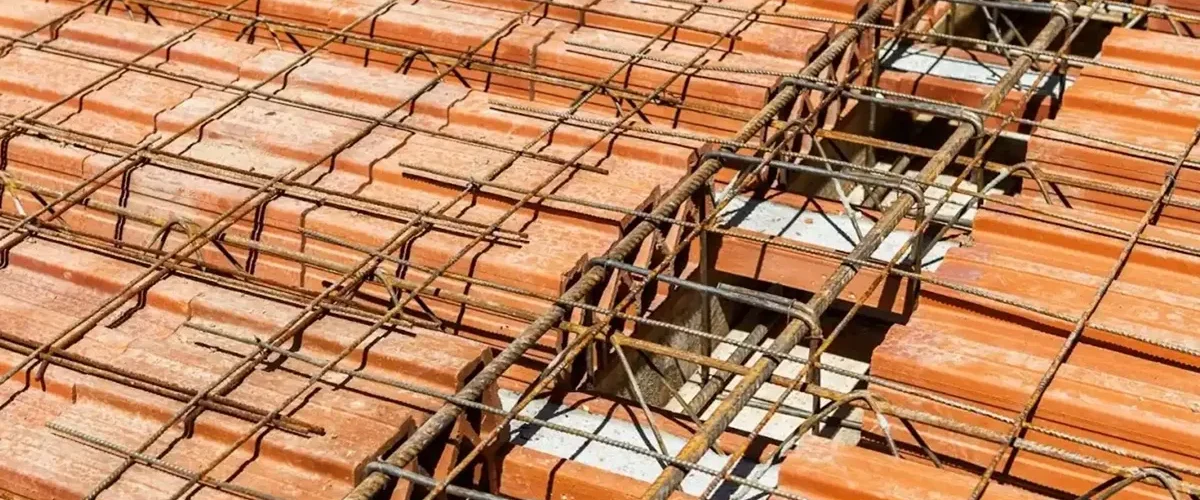 Laje pré-moldada com vigotas de concreto e blocos cerâmicos, mostrando armação de ferro na construção.