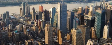 Panorama aéreo de Manhattan em Nova York, com arranha-céus iluminados pelo pôr do sol e o rio Hudson ao fundo.