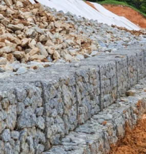 Muro de arrimo feito com gabiões cheios de pedras, utilizado para estabilizar talude.