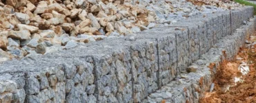 Muro de arrimo feito com gabiões cheios de pedras, utilizado para estabilizar talude.