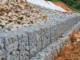 Muro de arrimo feito com gabiões cheios de pedras, utilizado para estabilizar talude.