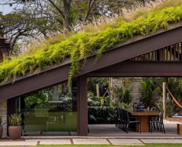 Casa moderna com telhado verde coberto por vegetação, integrando área externa com jardim e espaço de convivência.