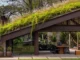 Casa moderna com telhado verde coberto por vegetação, integrando área externa com jardim e espaço de convivência.