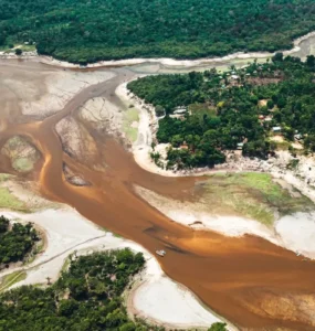 Rio da Amazônia com nível de água extremamente baixo, mostrando leito exposto, bancos de areia e floresta ao redor