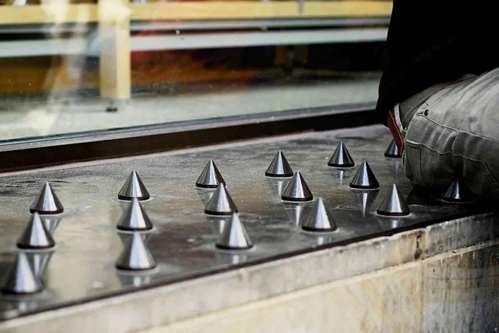 Superfície com cones metálicos pontiagudos usados como arquitetura hostil para evitar que pessoas se sentem ou permaneçam no local.