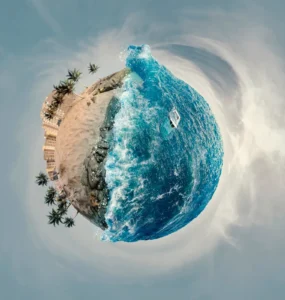 Efeito Little Planet mostrando uma praia com palmeiras e mar azul formando um mini planeta em imagem panorâmica 360 graus.