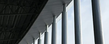 Pilares de concreto alinhados sustentando cobertura de edifício com estrutura metálica moderna