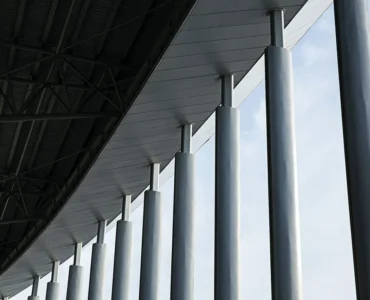 Pilares de concreto alinhados sustentando cobertura de edifício com estrutura metálica moderna