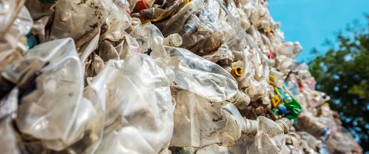 Pilha de resíduos sólidos plásticos compactados, com garrafas PET e embalagens descartáveis destinadas à reciclagem.