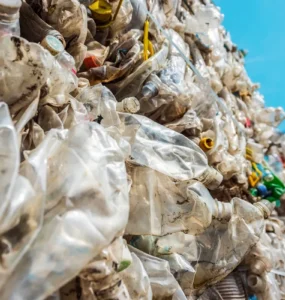Pilha de resíduos sólidos plásticos compactados, com garrafas PET e embalagens descartáveis destinadas à reciclagem.