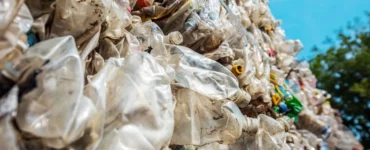 Pilha de resíduos sólidos plásticos compactados, com garrafas PET e embalagens descartáveis destinadas à reciclagem.