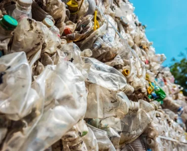 Pilha de resíduos sólidos plásticos compactados, com garrafas PET e embalagens descartáveis destinadas à reciclagem.