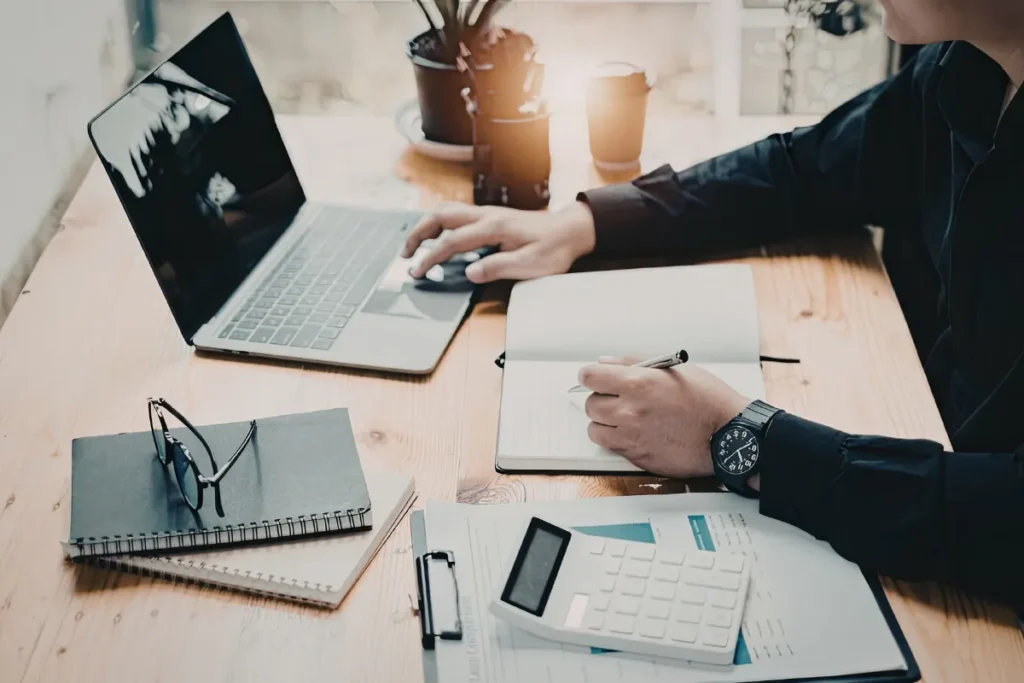 Pessoa usando laptop e escrevendo em uma agenda