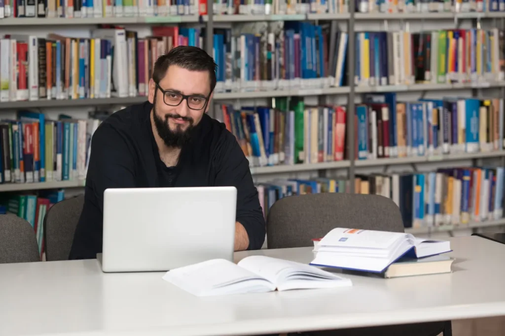 Homem trabalhando em seu laptop, em uma biblioteca