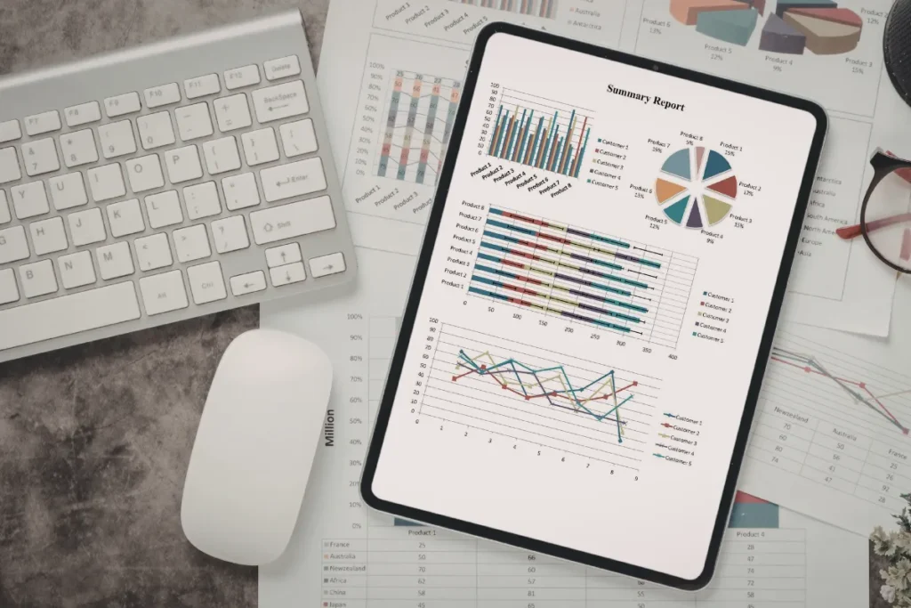 Mesa com teclado, mouse e tablet mostrando gráficos