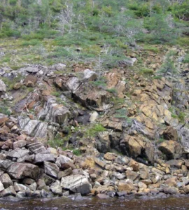 Encosta rochosa com diferentes blocos de pedra e vegetação espalhada em uma paisagem natural.