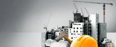 Capacete de segurança amarelo, martelo e plantas de projeto diante de prédios em construção com guindastes.