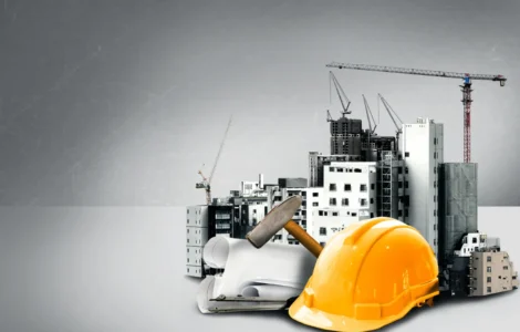 Capacete de segurança amarelo, martelo e plantas de projeto diante de prédios em construção com guindastes.