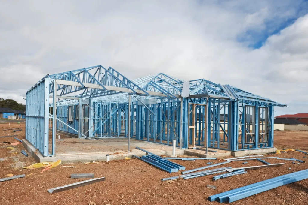 Estrutura completa de steel frame em construção com perfis metálicos azuis em terreno aberto
