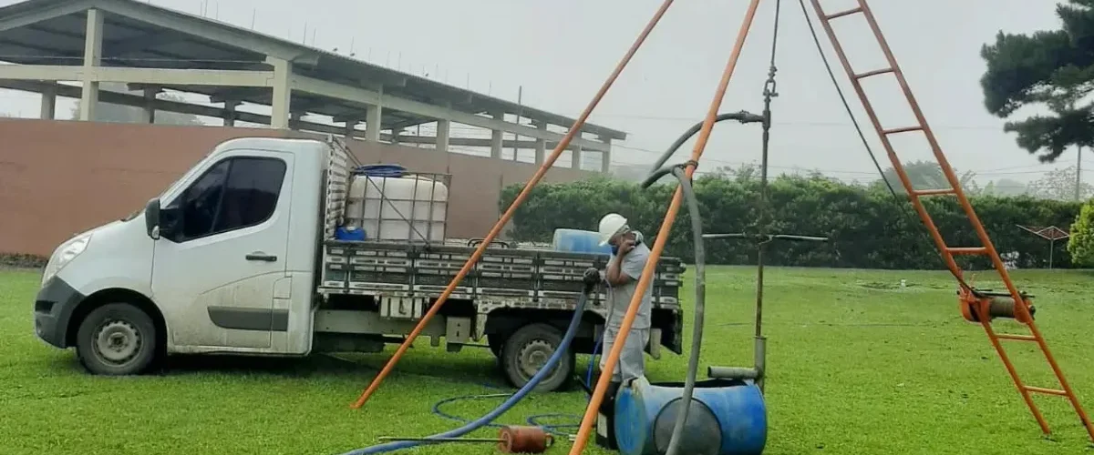 Equipamento de sondagem de solo montado em campo com técnico operando próximo a caminhão