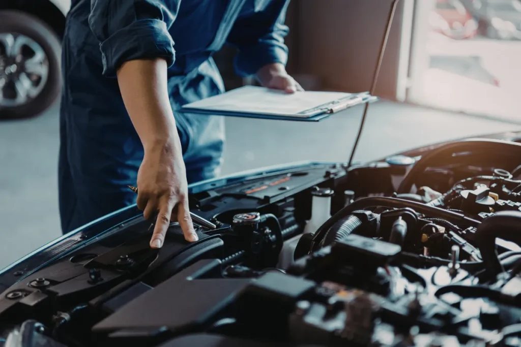 mecânico apontando para componentes do motor enquanto segura prancheta