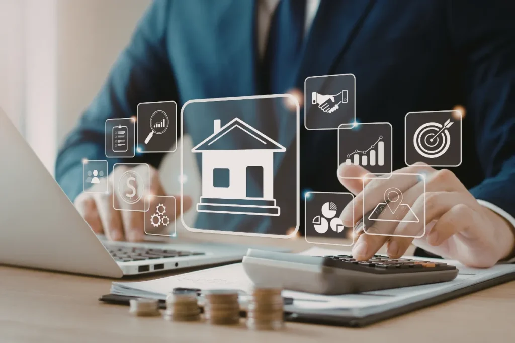 Pessoa utilizando calculadora e notebook com ícones digitais de casa e gráficos sobrepostos